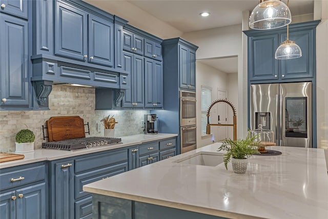 11 Hillsborough Dr E, Montgomery, TX 77356 - kitchen with appliances with stainless steel finishes, blue cabinets, a sink, hanging light fixtures, and backsplash
