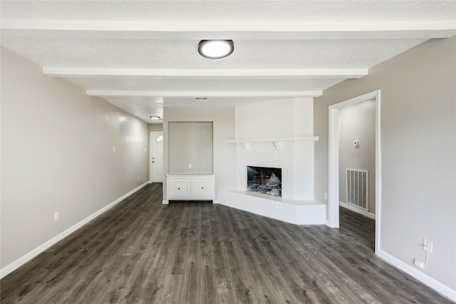 9627 Crooked Wood Ln, Houston, TX 77086 - unfurnished living room with beam ceiling, dark wood-style floors, baseboards, and a brick fireplace