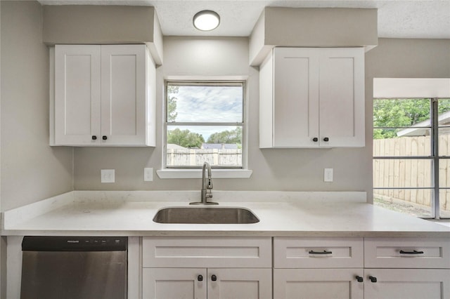 9627 Crooked Wood Ln, Houston, TX 77086 - kitchen featuring stainless steel dishwasher, a sink, light countertops, and white cabinetry