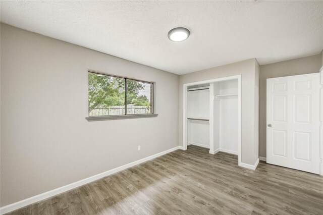 9627 Crooked Wood Ln, Houston, TX 77086 - unfurnished bedroom with wood finished floors, baseboards, and a closet