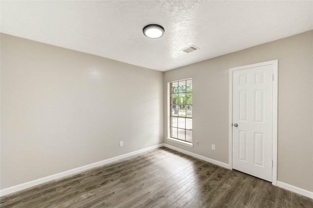 9627 Crooked Wood Ln, Houston, TX 77086 - empty room featuring dark wood-type flooring, baseboards, and a textured ceiling