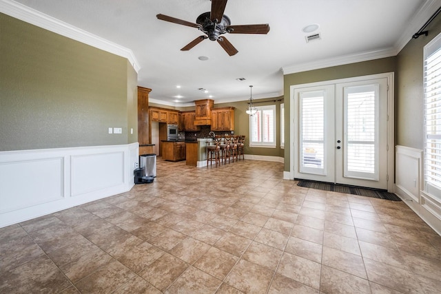 5925 Oak Leaf Ct, Conroe, TX 77304 - living area with a ceiling fan, crown molding, french doors, a decorative wall, and a wainscoted wall