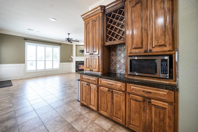 5925 Oak Leaf Ct, Conroe, TX 77304 - kitchen featuring stainless steel microwave, a ceiling fan, ornamental molding, tasteful backsplash, and a high end fireplace