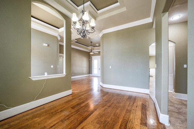 5925 Oak Leaf Ct, Conroe, TX 77304 - empty room featuring crown molding, arched walkways, a tray ceiling, a chandelier, and wood finished floors