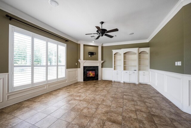 5925 Oak Leaf Ct, Conroe, TX 77304 - unfurnished living room with a decorative wall, wainscoting, a ceiling fan, crown molding, and a fireplace