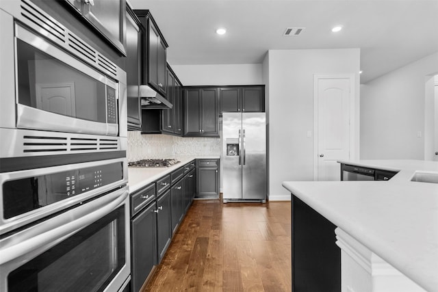 148 Gray Pine Grove Way, Conroe, TX 77318 - kitchen with appliances with stainless steel finishes, light countertops, recessed lighting, dark wood-style flooring, and backsplash