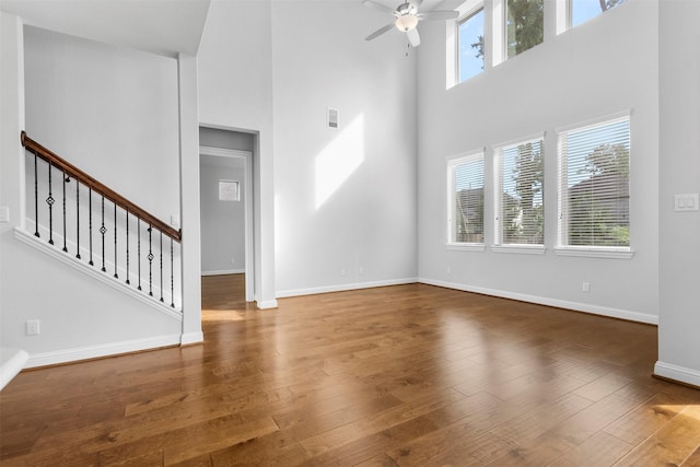 148 Gray Pine Grove Way, Conroe, TX 77318 - unfurnished living room featuring a towering ceiling, a ceiling fan, wood finished floors, and stairway