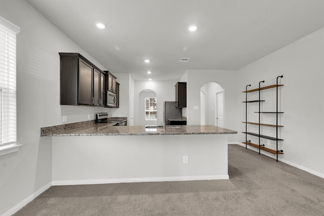 22807 Gentle Shadow Dr, Hockley, TX 77447 - kitchen with arched walkways, stainless steel appliances, light stone counters, light carpet, and recessed lighting