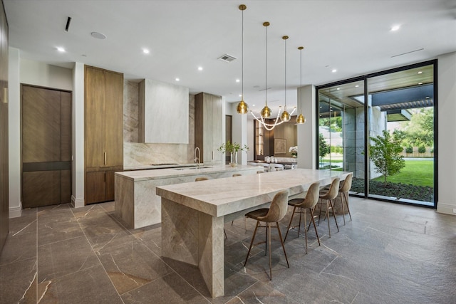 9010 Memorial Dr, Houston, TX 77024 - kitchen with modern cabinets, a large island, expansive windows, a sink, and dark marble finish floors