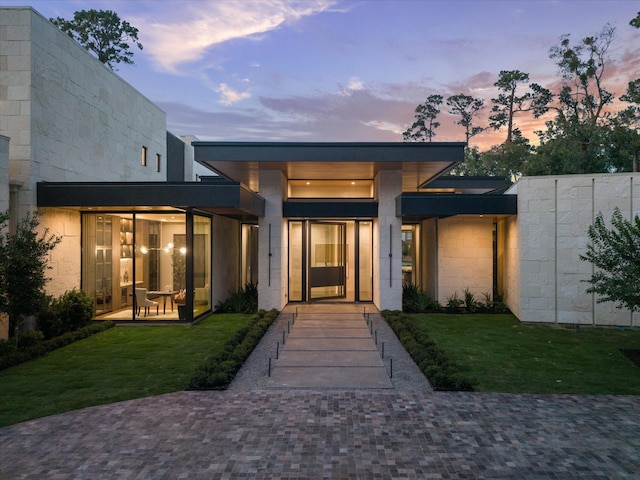 9010 Memorial Dr, Houston, TX 77024 - exterior entry at dusk with a lawn and concrete block siding