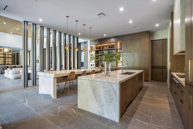 9010 Memorial Dr, Houston, TX 77024 - kitchen with modern cabinets, a sink, a spacious island, recessed lighting, and brown cabinets