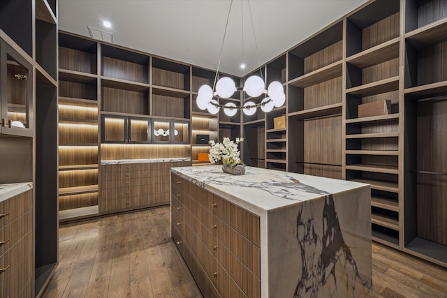 9010 Memorial Dr, Houston, TX 77024 - walk in closet featuring dark wood finished floors and a chandelier