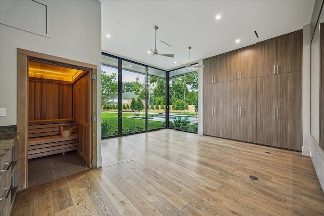 9010 Memorial Dr, Houston, TX 77024 - unfurnished living room with floor to ceiling windows, a ceiling fan, light wood-type flooring, and recessed lighting