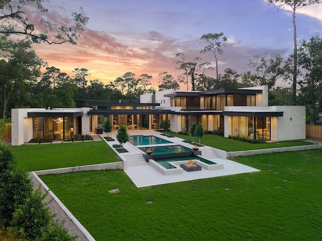 9010 Memorial Dr, Houston, TX 77024 - back of house at dusk featuring an in-ground hot tub, a patio area, an infinity pool, and a yard