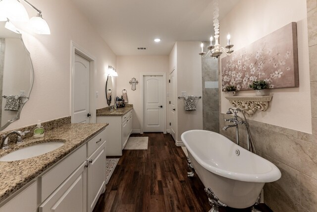 1812 Camellia Dr, Huntsville, TX 77340 - bathroom featuring two vanities, a freestanding bath, wood finished floors, a chandelier, and tile walls