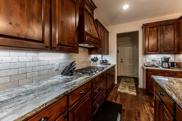 1812 Camellia Dr, Huntsville, TX 77340 - kitchen featuring premium range hood, dark wood-style floors, stainless steel gas cooktop, decorative backsplash, and dark stone counters