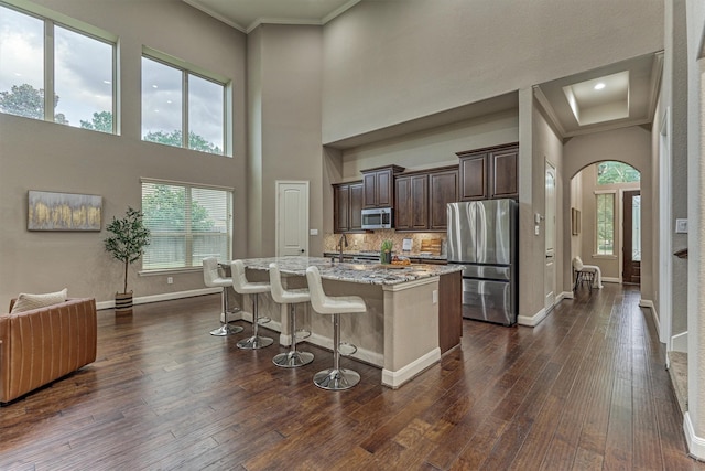 114 Cedar Brush Ct, Montgomery, TX 77316 - kitchen featuring stainless steel appliances, dark brown cabinets, a kitchen bar, dark wood-style flooring, and light stone countertops