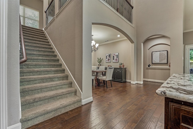 114 Cedar Brush Ct, Montgomery, TX 77316 - staircase with a chandelier, hardwood / wood-style flooring, arched walkways, a high ceiling, and ornamental molding