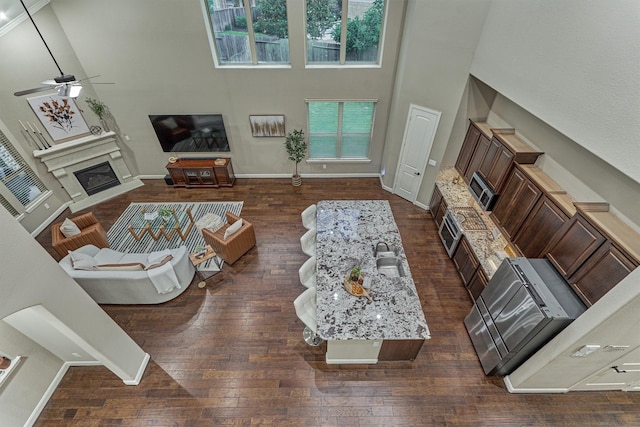 114 Cedar Brush Ct, Montgomery, TX 77316 - living area with ceiling fan, a high ceiling, dark wood-style flooring, a glass covered fireplace, and plenty of natural light