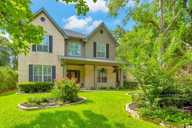 126 S Bluff Creek Cir, The Woodlands, TX 77382 - view of front of house featuring stone siding, a front yard, covered porch, a standing seam roof, and a metal roof