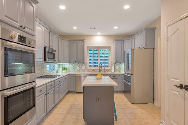 126 S Bluff Creek Cir, The Woodlands, TX 77382 - kitchen featuring gray cabinets, stainless steel appliances, light countertops, backsplash, and a center island