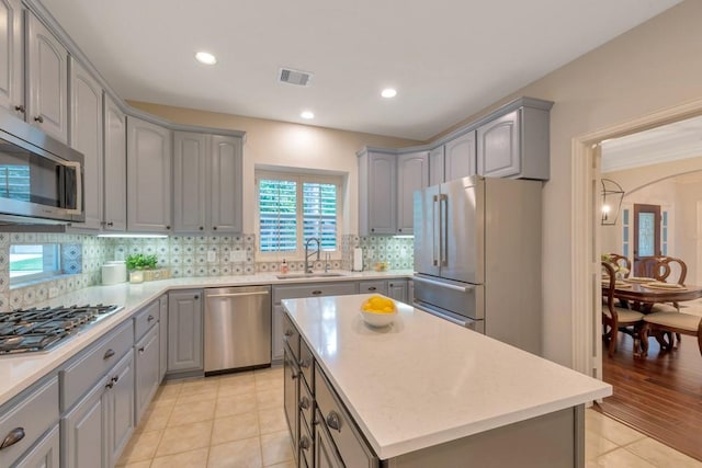 126 S Bluff Creek Cir, The Woodlands, TX 77382 - kitchen featuring appliances with stainless steel finishes, gray cabinetry, decorative backsplash, light countertops, and a kitchen island