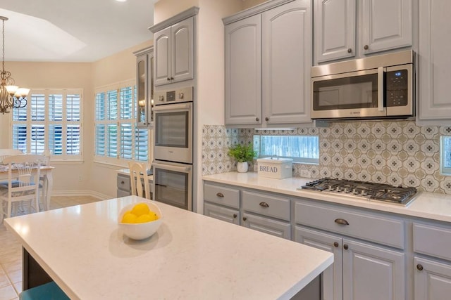 126 S Bluff Creek Cir, The Woodlands, TX 77382 - kitchen featuring appliances with stainless steel finishes, gray cabinetry, a chandelier, tasteful backsplash, and light countertops