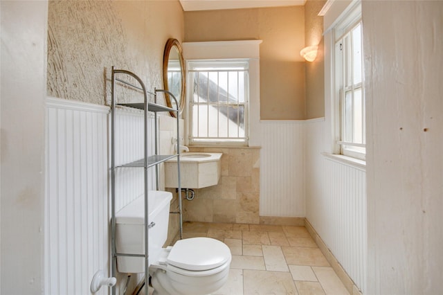239 Westheimer Rd, Houston, TX 77006 - bathroom with a wainscoted wall, toilet, and stone tile floors