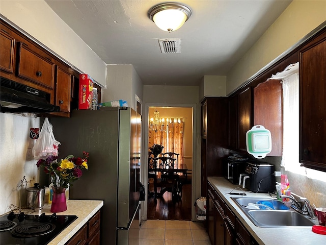 7727 Log Hollow Dr, Houston, TX 77040 - kitchen featuring a sink, light tile patterned floors, under cabinet range hood, black electric cooktop, and light countertops