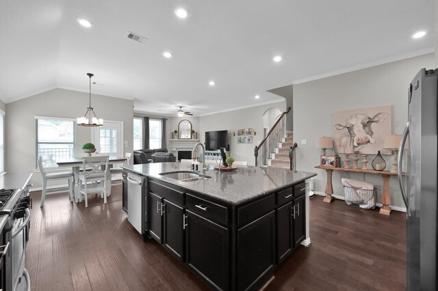 138 Verismo Ct, Montgomery, TX 77316 - kitchen featuring appliances with stainless steel finishes, dark cabinets, a fireplace, dark wood-style floors, and light stone counters