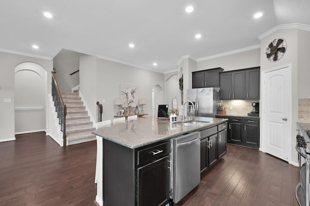 138 Verismo Ct, Montgomery, TX 77316 - kitchen featuring stainless steel appliances, arched walkways, light stone counters, dark wood finished floors, and recessed lighting