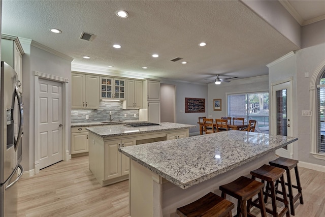 16 Waterberry Way, Montgomery, TX 77356 - kitchen featuring a center island, appliances with stainless steel finishes, light wood-style flooring, crown molding, and a sink