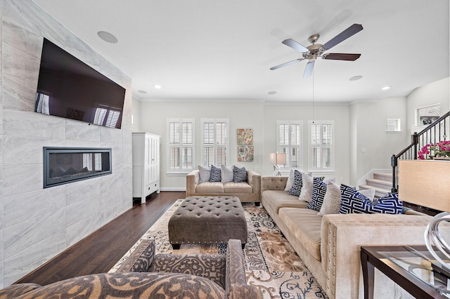 10812 Kyler Oaks Pl, Houston, TX 77043 - living room featuring wood finished floors, stairs, a tiled fireplace, ceiling fan, and crown molding