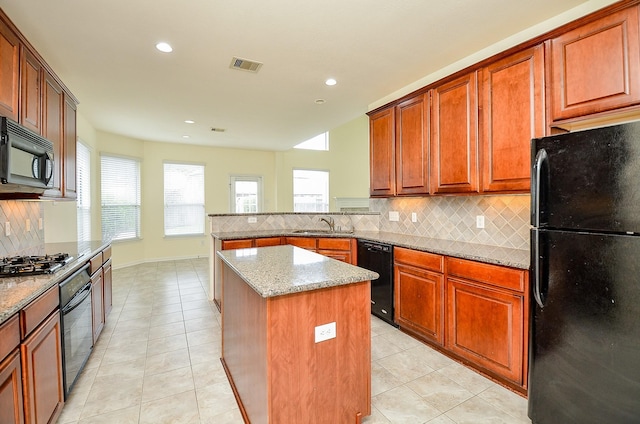 25314 Sandy Trace Ln, Katy, TX 77494 - kitchen with black appliances, backsplash, light stone countertops, a kitchen island, and light tile patterned flooring