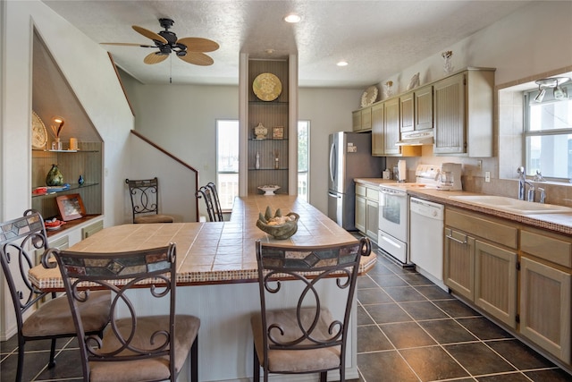 3101 Diane, Crystal Beach, TX 77650 - kitchen featuring white appliances, tile countertops, a breakfast bar, under cabinet range hood, and a sink