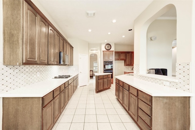 5810 Sequoia Trace Ct, Spring, TX 77379 - kitchen with arched walkways, tasteful backsplash, light tile patterned floors, recessed lighting, and stainless steel gas cooktop