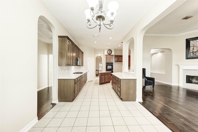 5810 Sequoia Trace Ct, Spring, TX 77379 - kitchen featuring open floor plan, light countertops, arched walkways, backsplash, and a fireplace