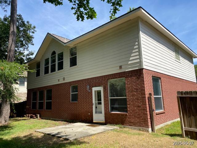 151 Prairie Dawn Cir, Conroe, TX 77385 - back of property featuring brick siding, a patio area, and a lawn