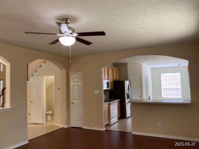 151 Prairie Dawn Cir, Conroe, TX 77385 - kitchen featuring white microwave, range, a ceiling fan, arched walkways, and wood finished floors