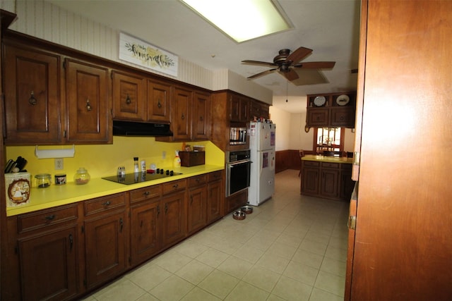 32226 Divot Dr, Waller, TX 77484 - kitchen with black appliances, a ceiling fan, under cabinet range hood, light countertops, and light tile patterned flooring