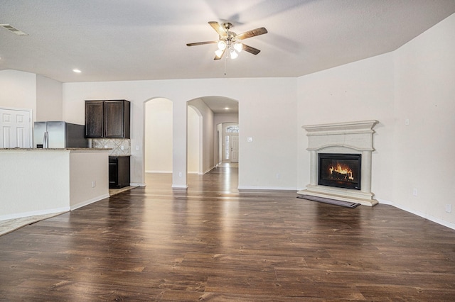 6843 Oaken Gate Way, Humble, TX 77338 - unfurnished living room with a ceiling fan, a glass covered fireplace, dark wood-style floors, arched walkways, and recessed lighting