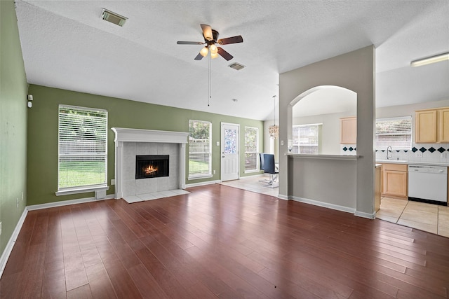 21055 Southern Colony Ct, Katy, TX 77449 - unfurnished living room featuring a ceiling fan, a tile fireplace, healthy amount of natural light, light wood-style flooring, and a textured ceiling