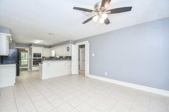 12903 Cluster Pine Dr, Cypress, TX 77429 - kitchen with stainless steel appliances, a breakfast bar, a ceiling fan, white cabinetry, and light tile patterned floors