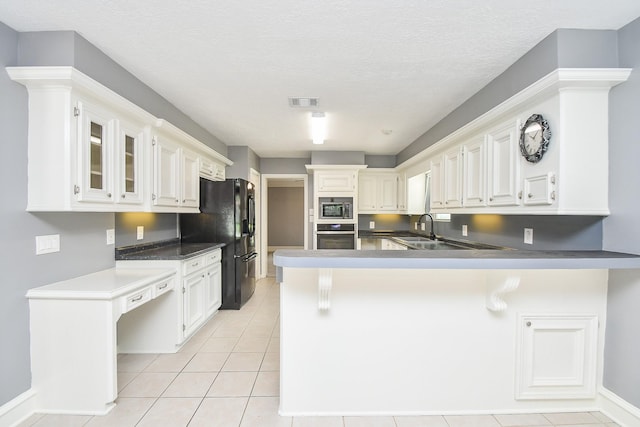 12903 Cluster Pine Dr, Cypress, TX 77429 - kitchen with stainless steel appliances, a peninsula, light tile patterned floors, glass insert cabinets, and white cabinetry