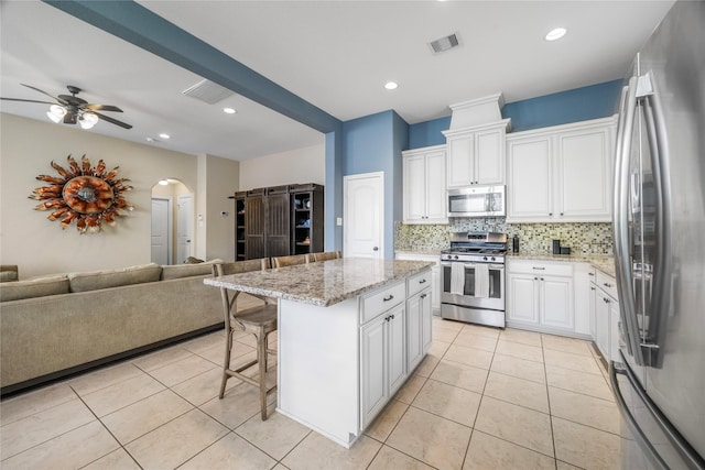 122 Cheswood Forest Dr, Montgomery, TX 77316 - kitchen featuring appliances with stainless steel finishes, open floor plan, arched walkways, tasteful backsplash, and a kitchen breakfast bar