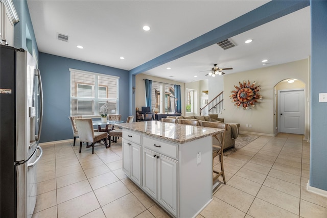 122 Cheswood Forest Dr, Montgomery, TX 77316 - kitchen with stainless steel refrigerator with ice dispenser, light tile patterned flooring, a breakfast bar area, white cabinetry, and recessed lighting