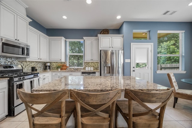 122 Cheswood Forest Dr, Montgomery, TX 77316 - kitchen featuring appliances with stainless steel finishes, backsplash, a kitchen breakfast bar, a kitchen island, and light tile patterned flooring