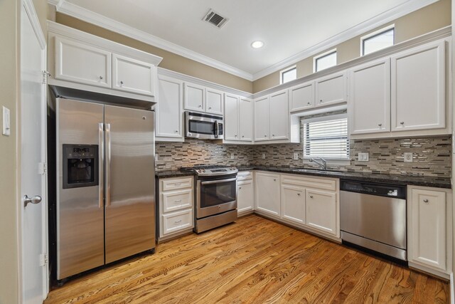11315 S Main St Unit 1205, Houston, TX 77025 - kitchen featuring stainless steel appliances, crown molding, white cabinetry, light wood finished floors, and tasteful backsplash