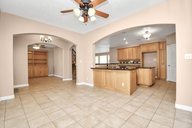 1019 N Country Club Dr, La Porte, TX 77571 - kitchen featuring dark countertops, light brown cabinets, arched walkways, ceiling fan, and light tile patterned floors