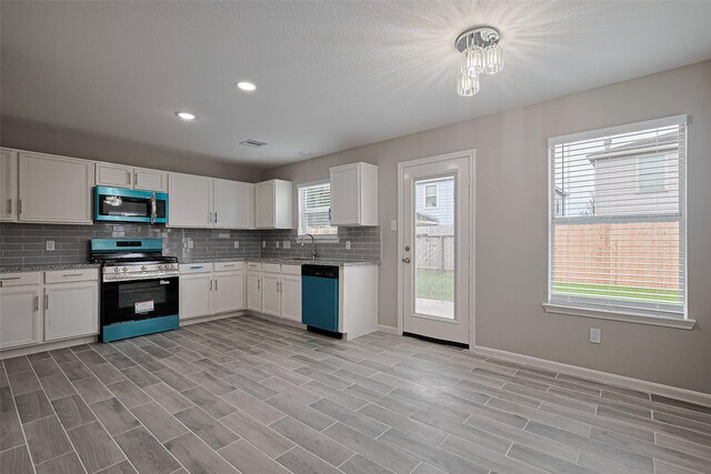 6723 Green Pear Ln, Houston, TX 77049 - kitchen featuring appliances with stainless steel finishes, decorative backsplash, white cabinets, light stone counters, and recessed lighting